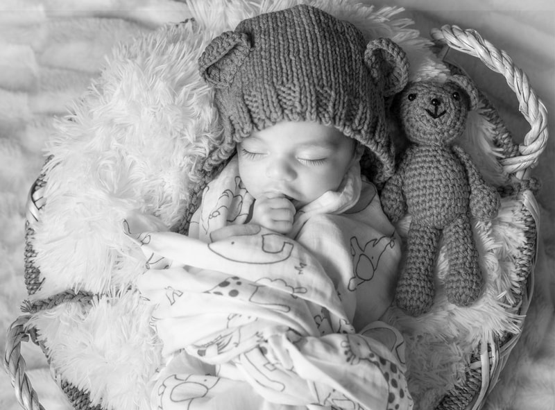 baby in hat with small teddy bear